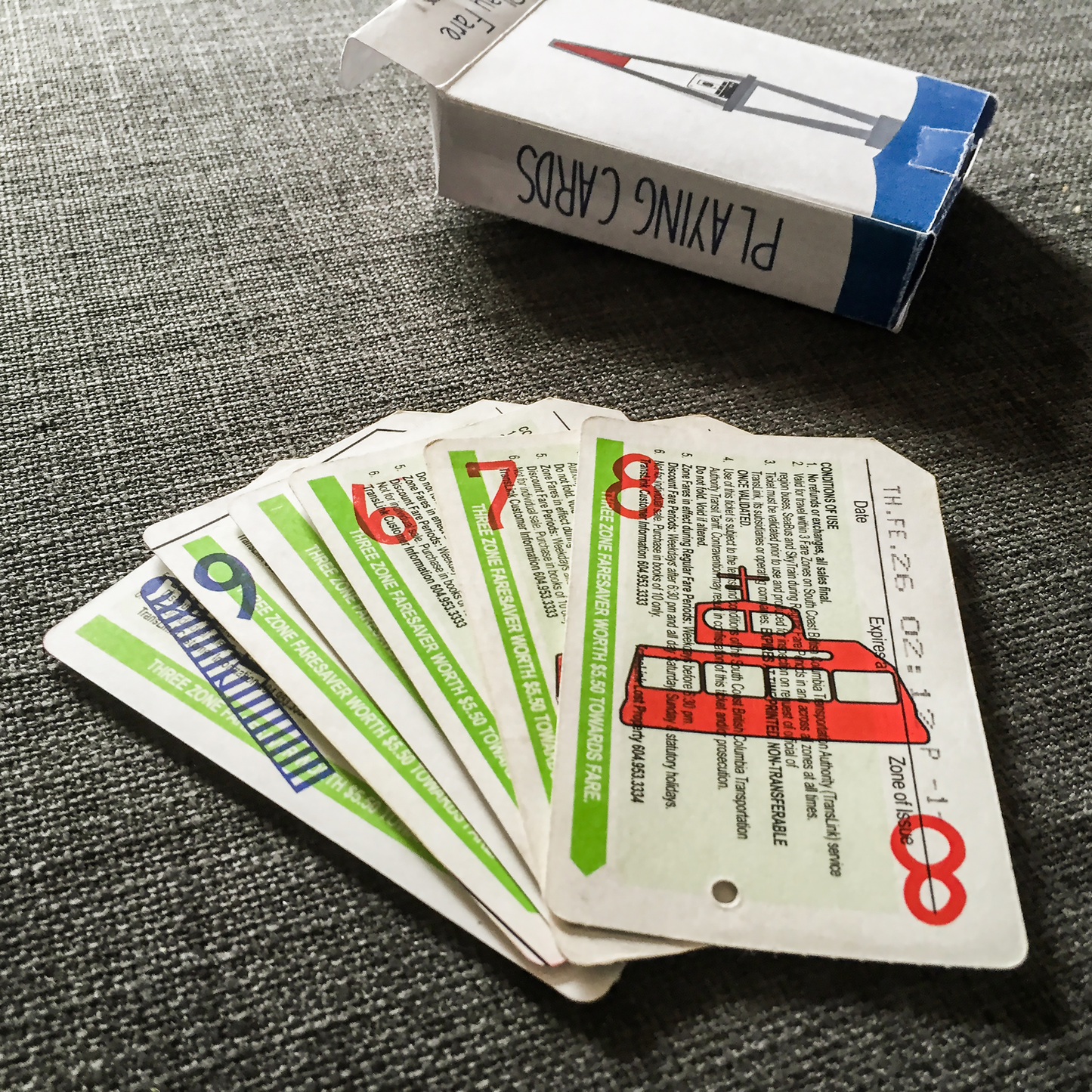 Repurposed transit fare cards, as deck of cards; illustrated box in background.